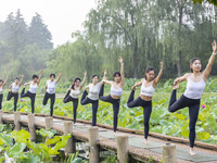 Yoga lovers are practicing yoga on the lotus pond trestle at Tiande Lake Park in Taizhou, China, on June 21, 2024. (