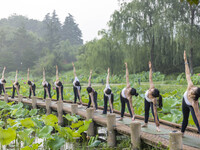 Yoga lovers are practicing yoga on the lotus pond trestle at Tiande Lake Park in Taizhou, China, on June 21, 2024. (