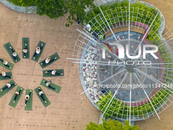 Yoga lovers are practicing yoga on the lotus pond trestle at Tiande Lake Park in Taizhou, China, on June 21, 2024. (