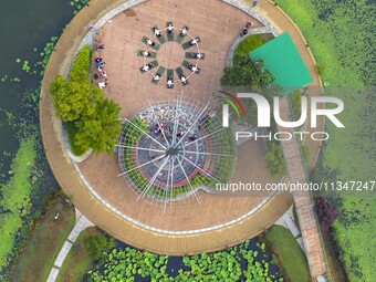 Yoga lovers are practicing yoga on the lotus pond trestle at Tiande Lake Park in Taizhou, China, on June 21, 2024. (