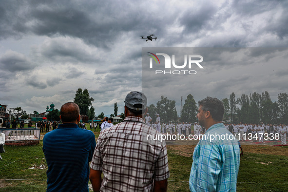 People are watching as a drone is flying during the 10th International Yoga Day Celebrations in Baramulla, Jammu and Kashmir, India, on June...