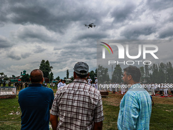 People are watching as a drone is flying during the 10th International Yoga Day Celebrations in Baramulla, Jammu and Kashmir, India, on June...