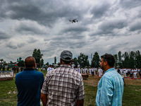 People are watching as a drone is flying during the 10th International Yoga Day Celebrations in Baramulla, Jammu and Kashmir, India, on June...