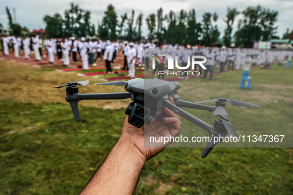 A man is holding his drone as he is waiting for the start of the 10th Yoga Day celebrations in Baramulla, Jammu and Kashmir, India, on June...