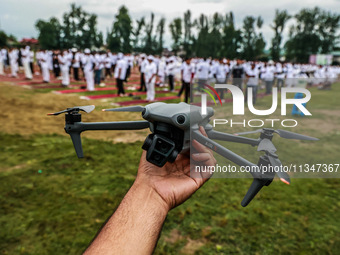 A man is holding his drone as he is waiting for the start of the 10th Yoga Day celebrations in Baramulla, Jammu and Kashmir, India, on June...