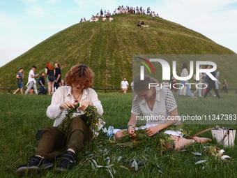 Women are making flower wreaths while celebrating the summer solstice during the 'Kupala Night' by the Krakus Mound in Krakow, Poland on Jun...