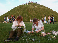 Women are making flower wreaths while celebrating the summer solstice during the 'Kupala Night' by the Krakus Mound in Krakow, Poland on Jun...