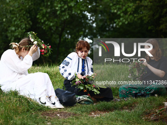 Women are making flower wreaths while celebrating the summer solstice during the 'Kupala Night' by the Krakus Mound in Krakow, Poland on Jun...