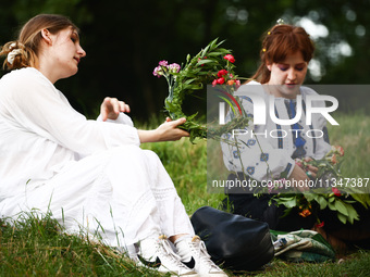 Women are making flower wreaths while celebrating the summer solstice during the 'Kupala Night' by the Krakus Mound in Krakow, Poland on Jun...