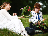 Women are making flower wreaths while celebrating the summer solstice during the 'Kupala Night' by the Krakus Mound in Krakow, Poland on Jun...