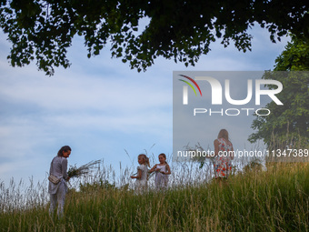 Women are picking wild plants while celebrating the summer solstice during the 'Kupala Night' by the Krakus Mound in Krakow, Poland on June...