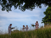 Women are picking wild plants while celebrating the summer solstice during the 'Kupala Night' by the Krakus Mound in Krakow, Poland on June...