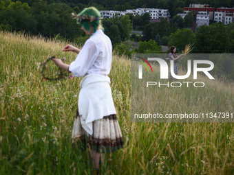 Women are picking wild plants while celebrating the summer solstice during the 'Kupala Night' by the Krakus Mound in Krakow, Poland on June...