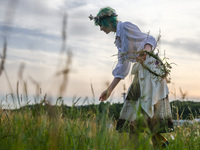 A girl is picking wild plants while celebrating the summer solstice during the 'Kupala Night' by the Krakus Mound in Krakow, Poland on June...