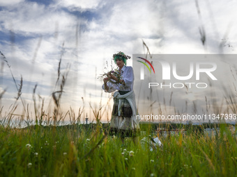 A girl is picking wild plants while celebrating the summer solstice during the 'Kupala Night' by the Krakus Mound in Krakow, Poland on June...