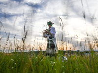 A girl is picking wild plants while celebrating the summer solstice during the 'Kupala Night' by the Krakus Mound in Krakow, Poland on June...