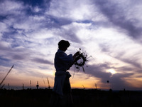 A girl is picking wild plants while celebrating the summer solstice during the 'Kupala Night' by the Krakus Mound in Krakow, Poland on June...