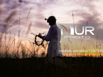 A girl is picking wild plants while celebrating the summer solstice during the 'Kupala Night' by the Krakus Mound in Krakow, Poland on June...