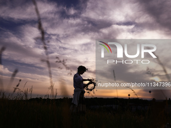 A girl is picking wild plants while celebrating the summer solstice during the 'Kupala Night' by the Krakus Mound in Krakow, Poland on June...