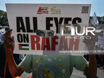 A pro-Palestinian activist is taking part in a protest against Israeli attacks on Gaza and Rafah (refugee camp) with a poster in Malang City...