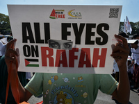 A pro-Palestinian activist is taking part in a protest against Israeli attacks on Gaza and Rafah (refugee camp) with a poster in Malang City...