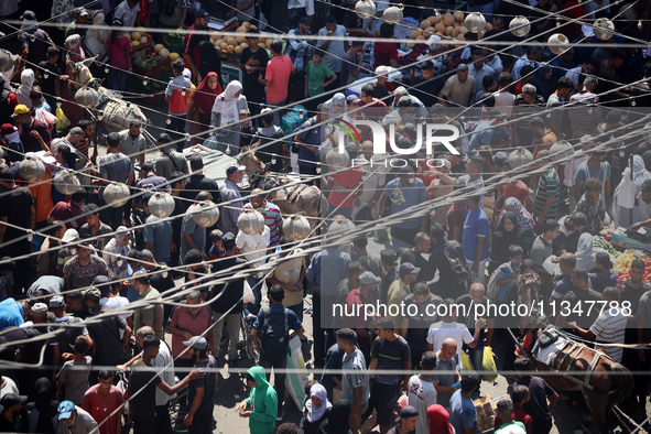 People are walking in a market in Deir al-Balah in the central Gaza Strip, on June 21, 2024, as the conflict in the Palestinian territory be...