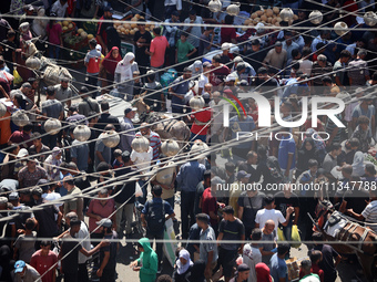 People are walking in a market in Deir al-Balah in the central Gaza Strip, on June 21, 2024, as the conflict in the Palestinian territory be...