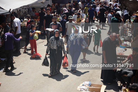 People are walking in a market in Deir al-Balah in the central Gaza Strip, on June 21, 2024, as the conflict in the Palestinian territory be...