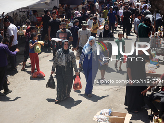 People are walking in a market in Deir al-Balah in the central Gaza Strip, on June 21, 2024, as the conflict in the Palestinian territory be...