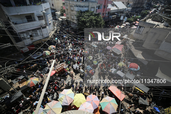 People are walking in a market in Deir al-Balah in the central Gaza Strip, on June 21, 2024, as the conflict in the Palestinian territory be...