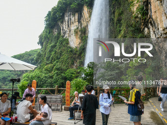 Tourists are viewing a waterfall at the Maling River Canyon scenic spot in Xingyi, China, on June 21, 2024. (