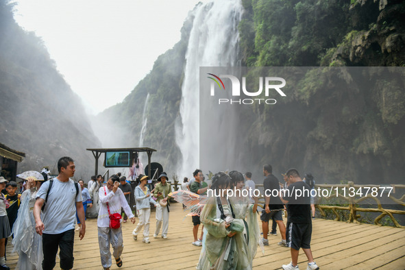 Tourists are viewing a waterfall at the Maling River Canyon scenic spot in Xingyi, China, on June 21, 2024. 