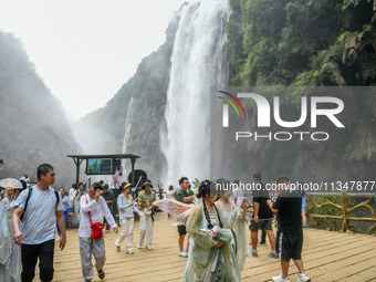 Tourists are viewing a waterfall at the Maling River Canyon scenic spot in Xingyi, China, on June 21, 2024. (