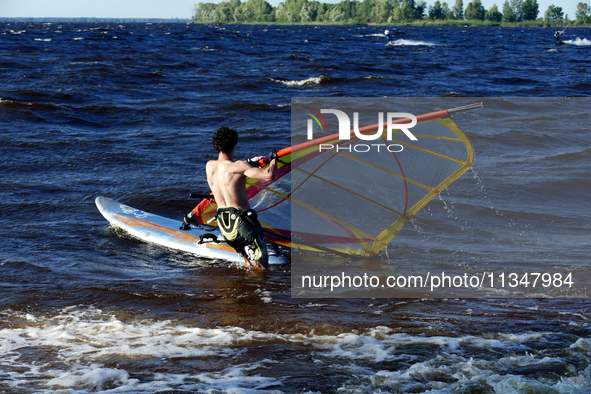 A man is practicing windsurfing on the Kremenchuk Reservoir in Cherkasy, Ukraine, on June 20, 2024. NO USE RUSSIA. NO USE BELARUS. 