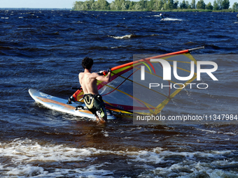 A man is practicing windsurfing on the Kremenchuk Reservoir in Cherkasy, Ukraine, on June 20, 2024. NO USE RUSSIA. NO USE BELARUS. (