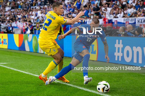 Mykola Matvienko of Ukraine is battling for possession with Lukas Haraslin of Slovakia (L-R)  during the UEFA EURO 2024 group stage match be...