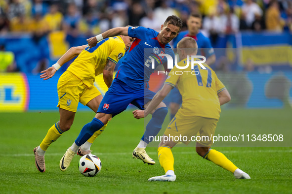 Peter Pekarik of Slovakia is battling for possession with Mykhailo Mudryk and Oleksandr Zinchenko of Ukraine  during the UEFA EURO 2024 grou...