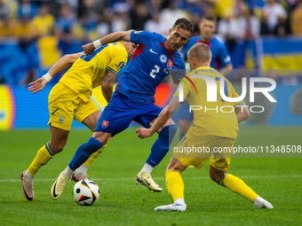 Peter Pekarik of Slovakia is battling for possession with Mykhailo Mudryk and Oleksandr Zinchenko of Ukraine  during the UEFA EURO 2024 grou...