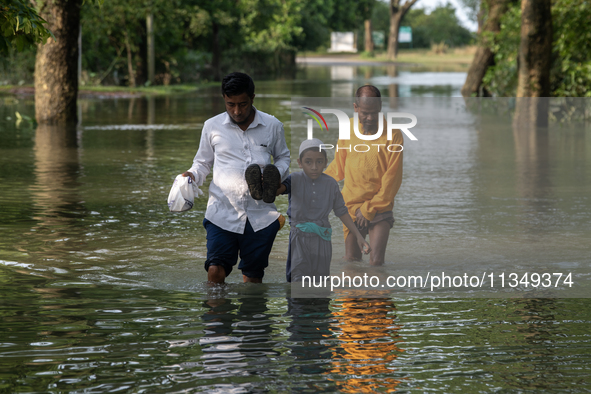 People are wading through floodwater in Gowainghat, Sylhet, Bangladesh, on Friday, June 21, 2024. 