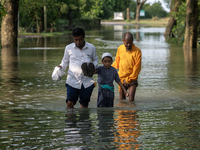 People are wading through floodwater in Gowainghat, Sylhet, Bangladesh, on Friday, June 21, 2024. (