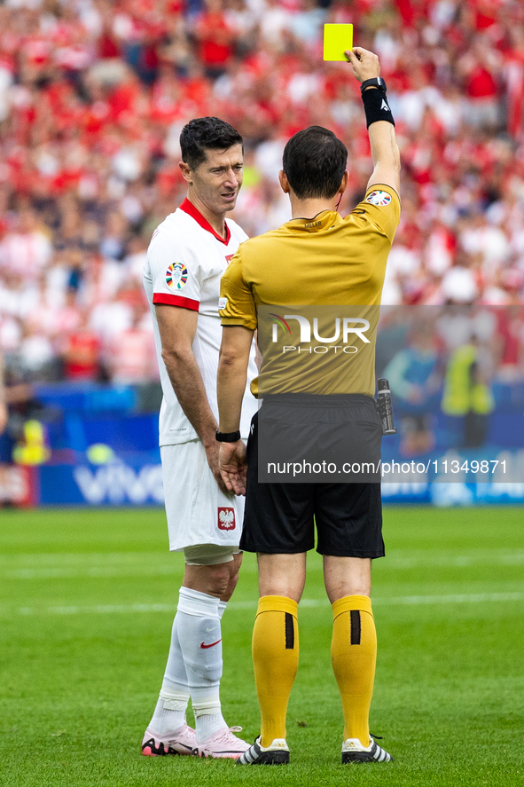 Referee Umut Meler  is showing  a yellow card to Robert Lewandowski  during the UEFA Euro 2024 Group D match between Poland v Austria, at th...