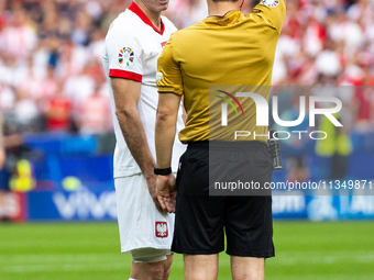 Referee Umut Meler  is showing  a yellow card to Robert Lewandowski  during the UEFA Euro 2024 Group D match between Poland v Austria, at th...