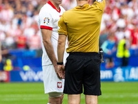 Referee Umut Meler  is showing  a yellow card to Robert Lewandowski  during the UEFA Euro 2024 Group D match between Poland v Austria, at th...