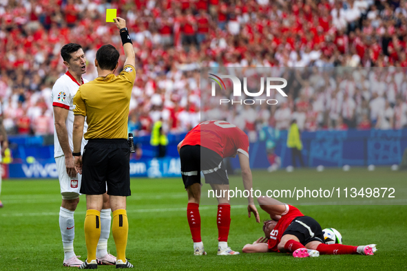 Referee Umut Meler  is showing  a yellow card to Robert Lewandowski  during the UEFA Euro 2024 Group D match between Poland v Austria, at th...