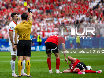 Referee Umut Meler  is showing  a yellow card to Robert Lewandowski  during the UEFA Euro 2024 Group D match between Poland v Austria, at th...