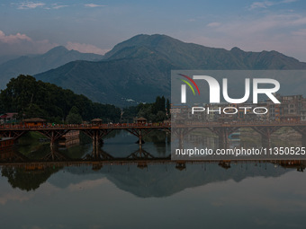 People are walking on Zero Bridge in Rajbagh on a cloudy day in Srinagar, Jammu and Kashmir, India, on June 22, 2024 (