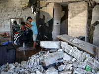 A barber is cutting the hair of a man in the ruins of his destroyed salon, which was destroyed by Israeli strikes, in al-Bureij refugee camp...