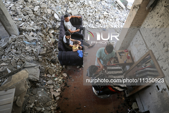 A barber is cutting the hair of a man in the ruins of his destroyed salon, which was destroyed by Israeli strikes, in al-Bureij refugee camp...