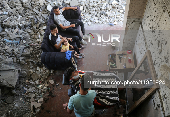 A barber is cutting the hair of a man in the ruins of his destroyed salon, which was destroyed by Israeli strikes, in al-Bureij refugee camp...