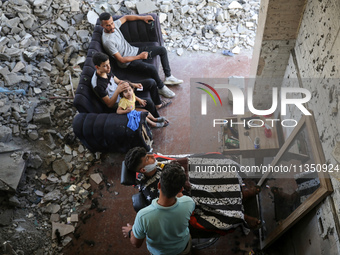 A barber is cutting the hair of a man in the ruins of his destroyed salon, which was destroyed by Israeli strikes, in al-Bureij refugee camp...